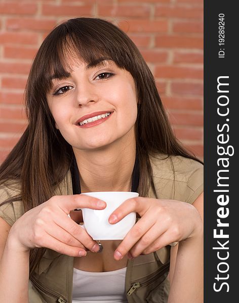 Pretty girl with a cup on the background of a red wall