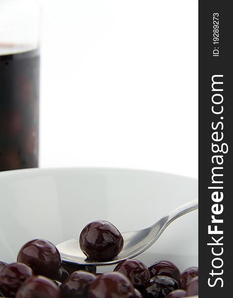 Single red cherry on a spoon with jar in the background. Single red cherry on a spoon with jar in the background