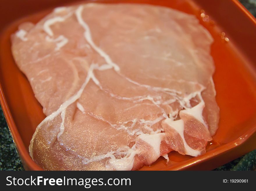 Raw sliced pork on red plate ready for cooking