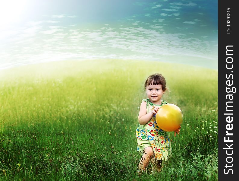 The child playing a ball on the meadow filled in with the sun