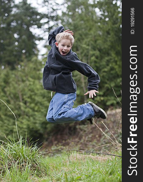 Young boy jumping in a feild of grass.