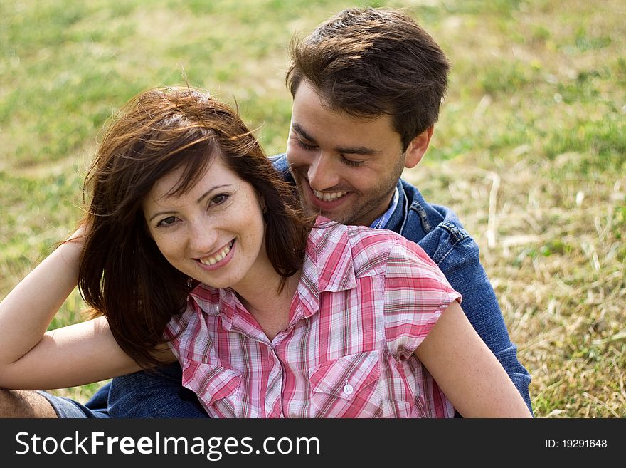 A young couple in love in a park hugging and kissing playing