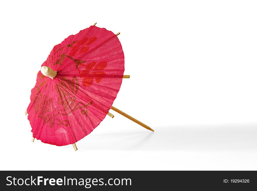 Red paper umbrella for cocktails, lying on a white background. Red paper umbrella for cocktails, lying on a white background