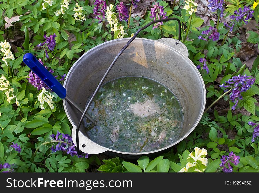 Outdoor summer. Cooks porridge in a pot on the fire. Outdoor summer. Cooks porridge in a pot on the fire