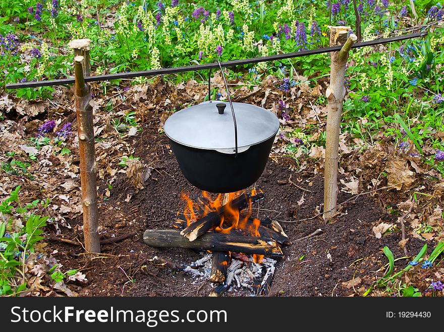 Outdoor summer. Cooks porridge in a pot on the fire. Outdoor summer. Cooks porridge in a pot on the fire