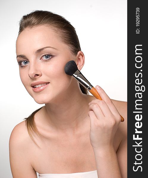 Woman using a powder brush against a white background
