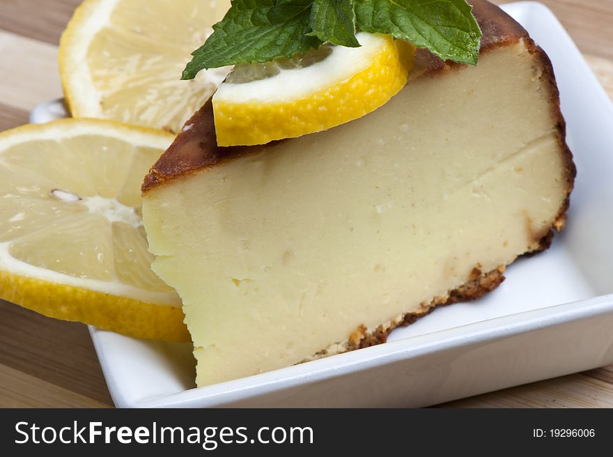 A piece of lemon cake decorated with lemon slices and mint leaves