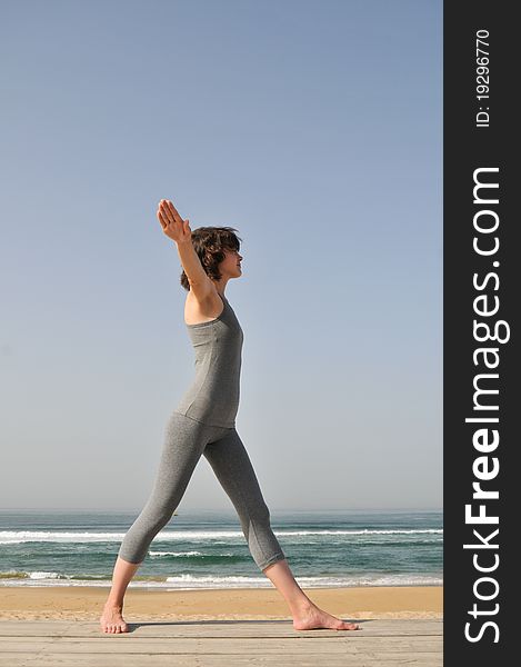 Image of the young woman in grey wear doing exercises on the beach. Image of the young woman in grey wear doing exercises on the beach