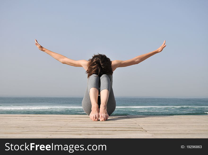 Young Woman Doing Exercises On The Beach