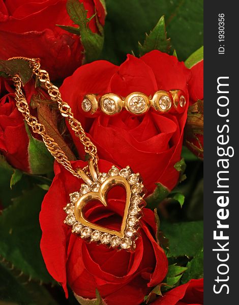 A diamond pendant and a diamond ring on a bunch of red roses. A diamond pendant and a diamond ring on a bunch of red roses