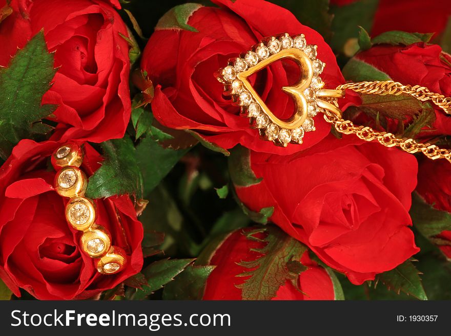 A diamond pendant and a diamond ring on a bunch of red roses. A diamond pendant and a diamond ring on a bunch of red roses