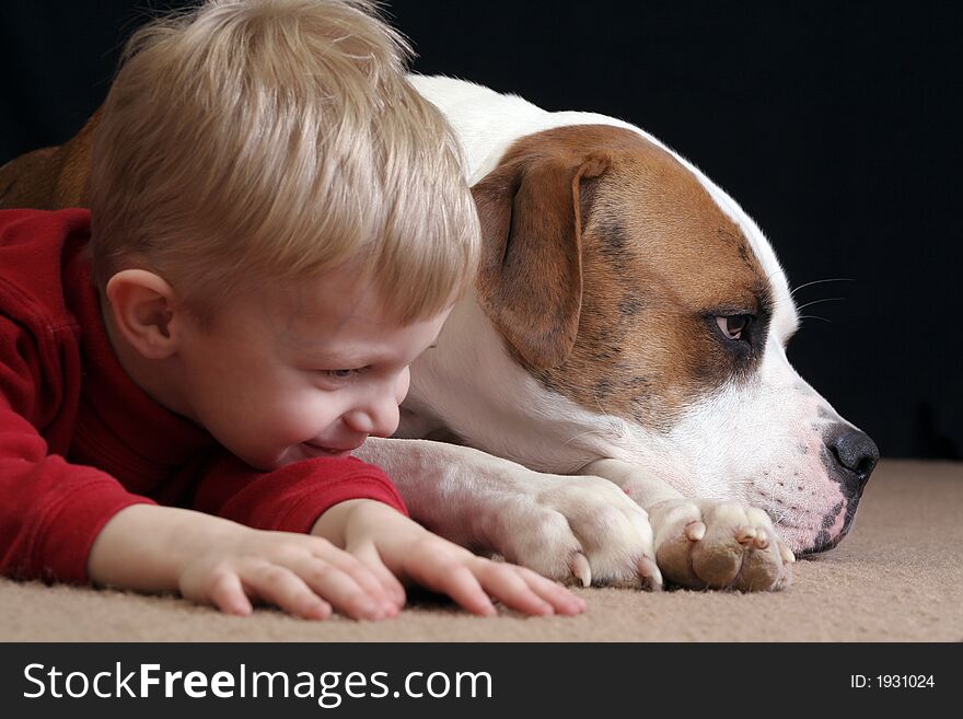 A little boy lays down like her cute puppy, an American Bulldog. A little boy lays down like her cute puppy, an American Bulldog.