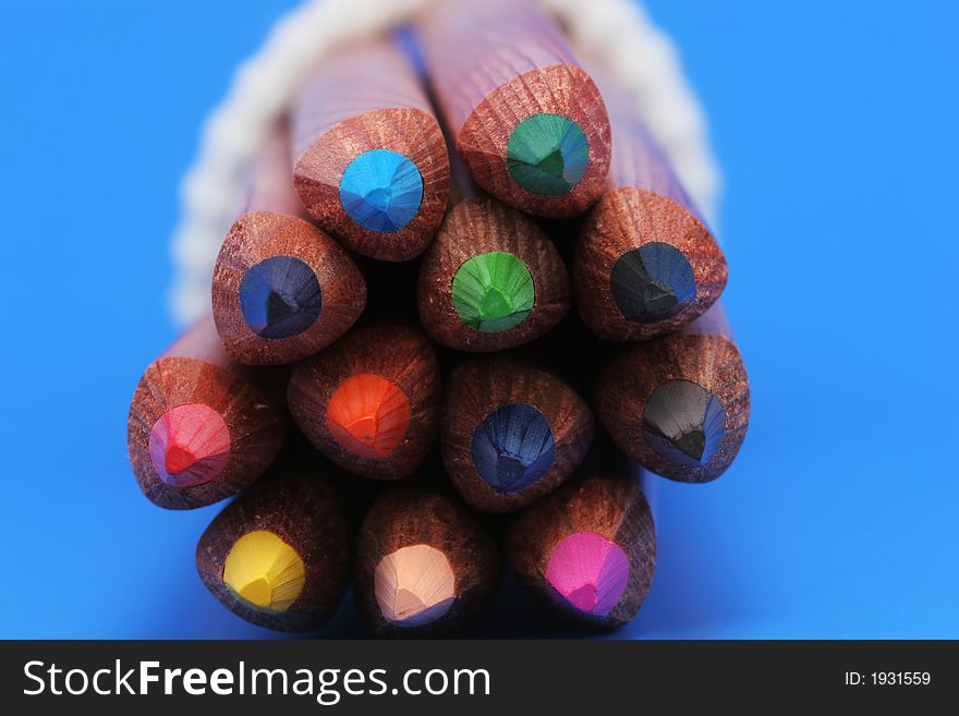 A macro shot of the front end of a group of colored pencils, isolated on blue. A macro shot of the front end of a group of colored pencils, isolated on blue