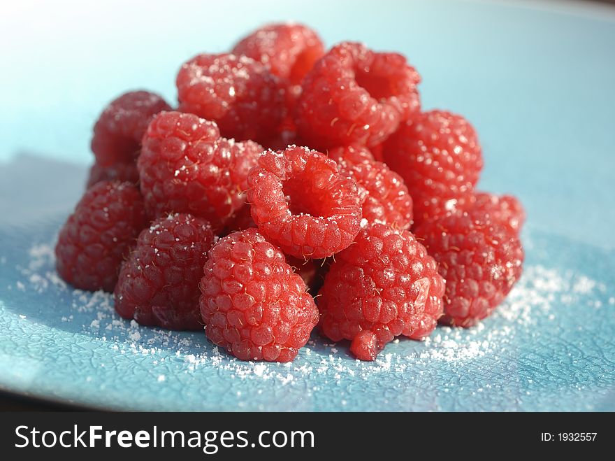 Delicious red raspberries on a blue plate. Delicious red raspberries on a blue plate