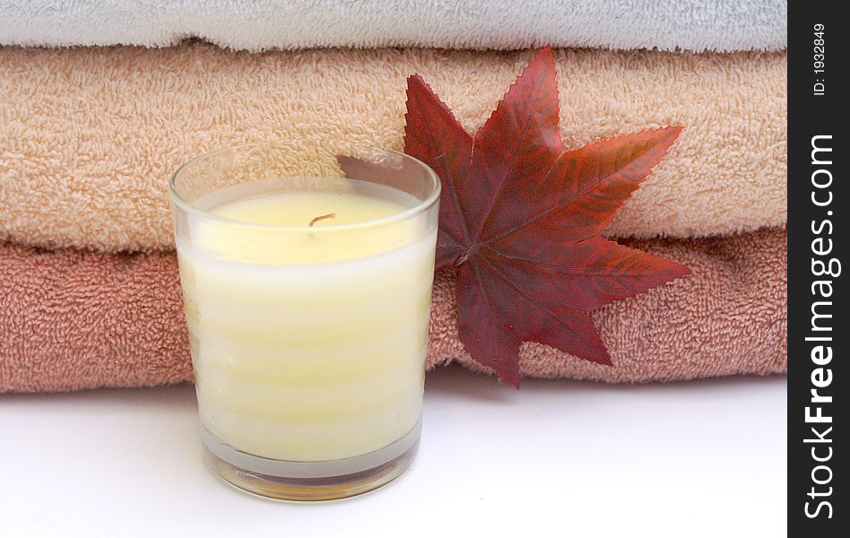 Bathroom relaxation with fall leaf, peach, white and russeyy stacked towels and scented cream candle. Bathroom relaxation with fall leaf, peach, white and russeyy stacked towels and scented cream candle