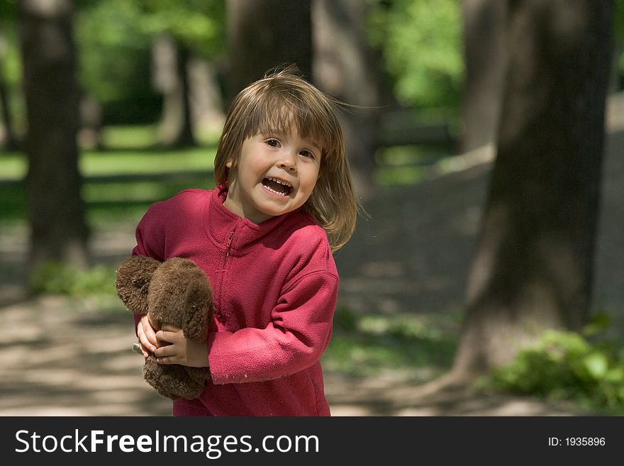 The little girl runs on a wood with a toy in hands. The little girl runs on a wood with a toy in hands