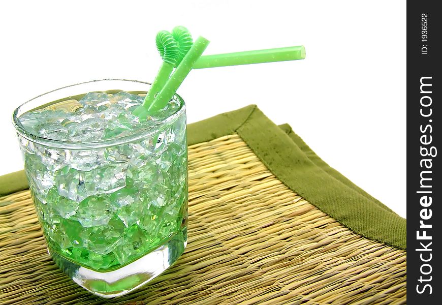 A nice collage of a glass containing a green drink (pisang) on the rocks, standing on a straw underground. A nice collage of a glass containing a green drink (pisang) on the rocks, standing on a straw underground.