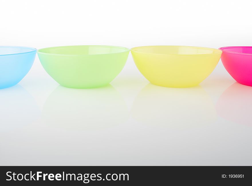 Four colored plastic vases on reflective white background