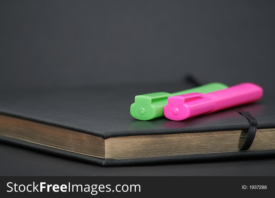 Writing book with golden pages and green and orange markers on top. Writing book with golden pages and green and orange markers on top