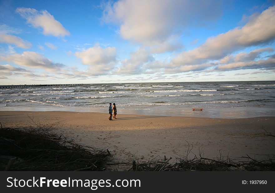 The man and the woman walk on a winter beach. Coast of the Baltic sea