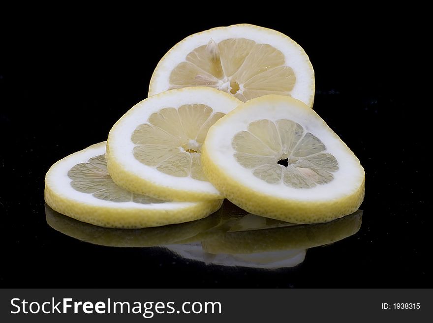 A sliced lemon with reflection showing in black surface. A sliced lemon with reflection showing in black surface