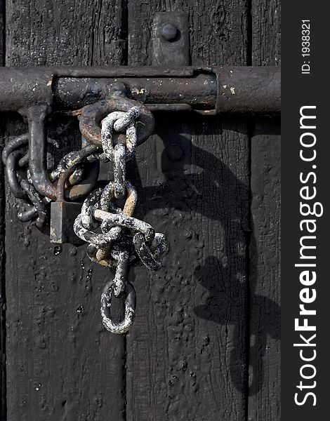 An old chain and padlock used to lock wooden door. An old chain and padlock used to lock wooden door