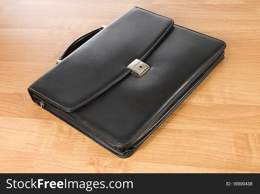 Fashionable leather briefcase on a  wooden table still life