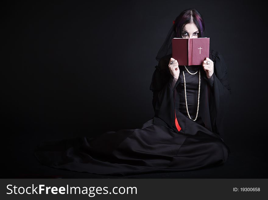 A gothic girl with the Bible. Isolated on a black bachground
