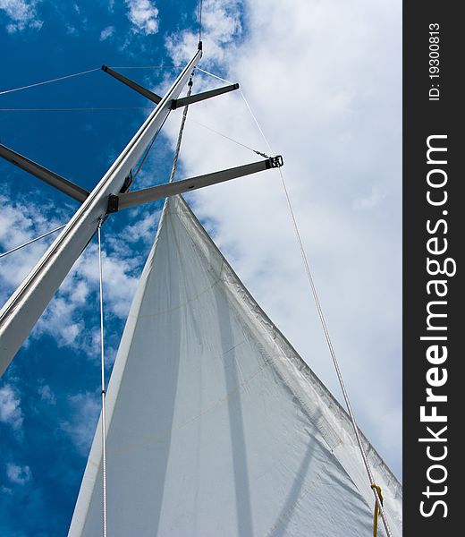 Yacht mast with the sail on the blue sky