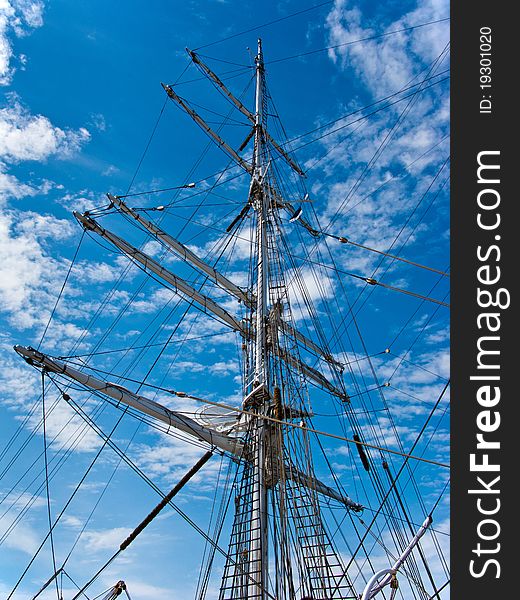 Ship mast with housed sails on the blue sky