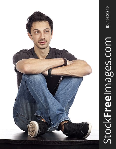 Young male fashion model sitting on a black table. High resolution image taken in studio. Isolated on pure white background with copy space for your ad. Part of photo series. Young male fashion model sitting on a black table. High resolution image taken in studio. Isolated on pure white background with copy space for your ad. Part of photo series.