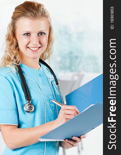 Beautiful young doctor with file folder and stethoscope in hospital