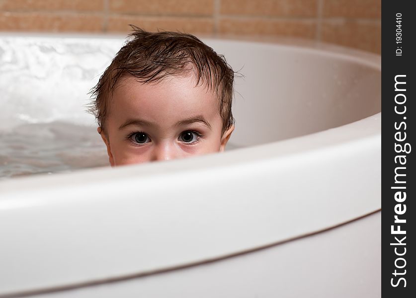 Child sits in water in bathroom and just look. Child sits in water in bathroom and just look