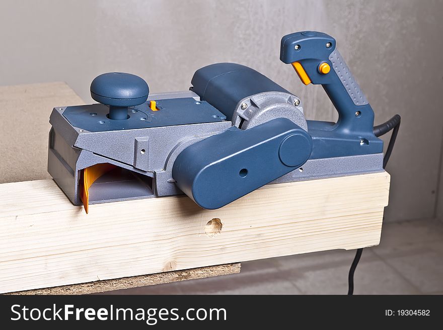 Close-up of a construction worker's hand and power tool while planing a piece of wood trim for a project. Close-up of a construction worker's hand and power tool while planing a piece of wood trim for a project.