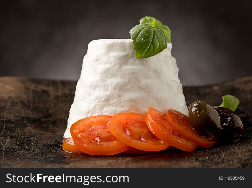 Photo of delicious ricotta cheese with tomatoes on wooden table with basil
