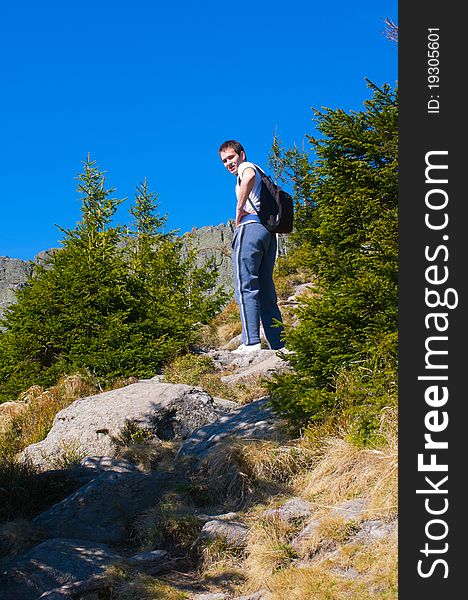 Man with backpack on a rocky path on the mountain looking behind. Man with backpack on a rocky path on the mountain looking behind.