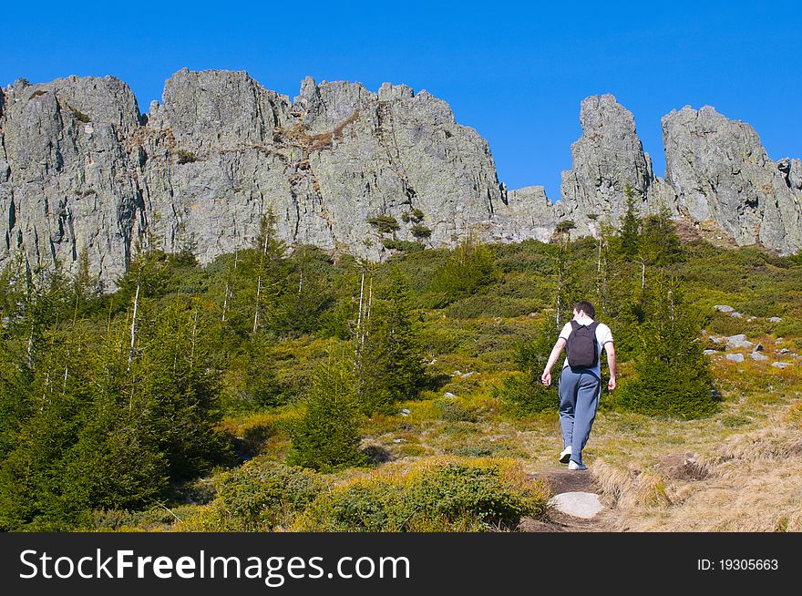 Man with backpack and cliff with blue clear sky in the background. Man with backpack and cliff with blue clear sky in the background.