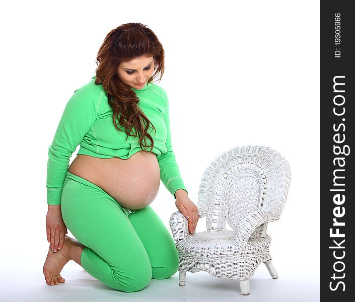 Pregnant woman kneeling next to a small white chair