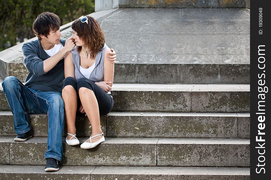 Portrait of young love couple sitting together on steps of a building