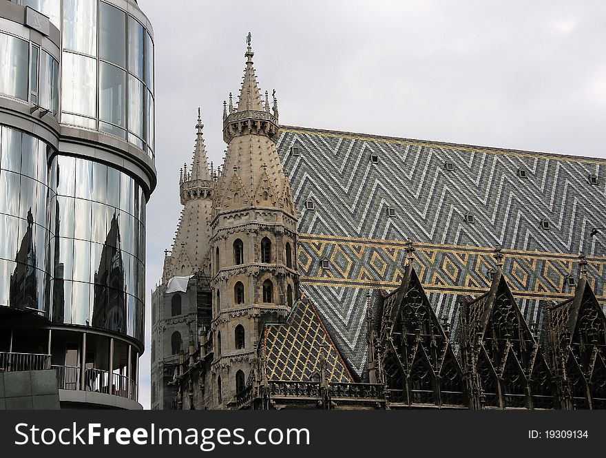 Mosaic roof of St. Stephen's Cathedral in Vienna and its reflection in the mirrored facade of the modern house