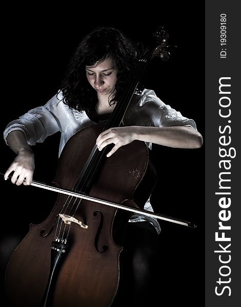 Girl playing cello, in black background