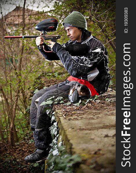 Paintball player aiming with marker in grunge background