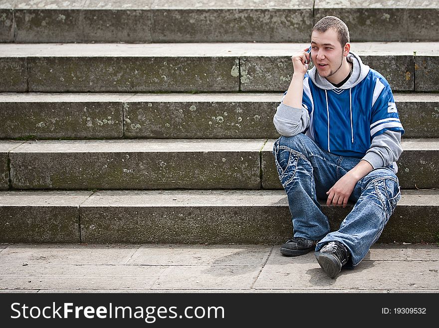 Young man sitting on stairs and talking on the phone