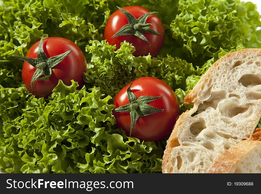 Three tomatoes are in a lettuce with two pices of bread. Three tomatoes are in a lettuce with two pices of bread