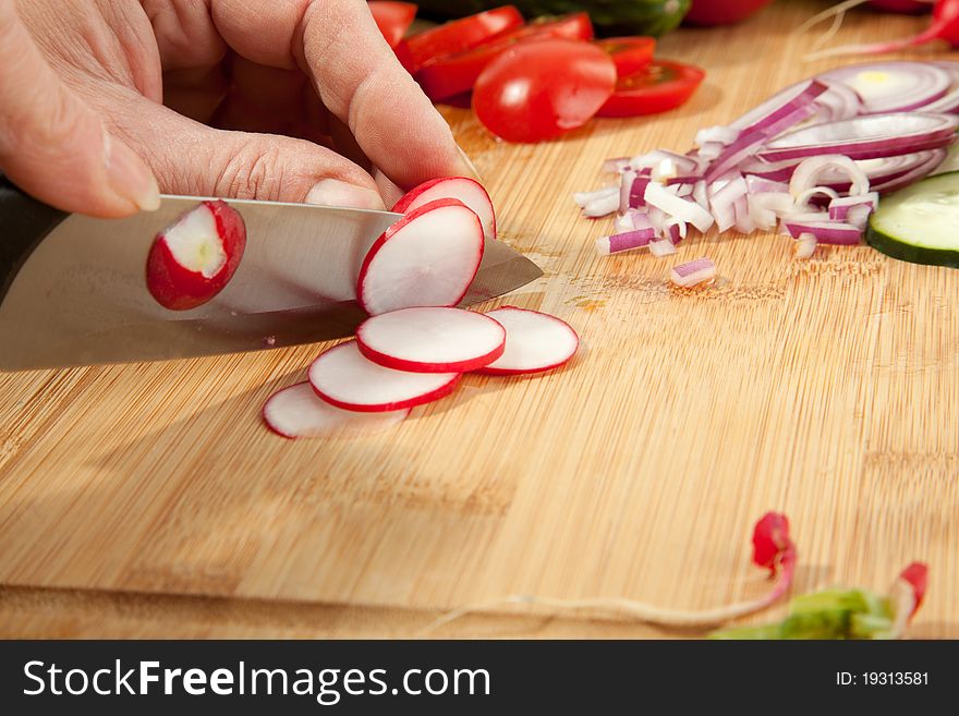 A woman is slicing a radish on a wooden board. A woman is slicing a radish on a wooden board.