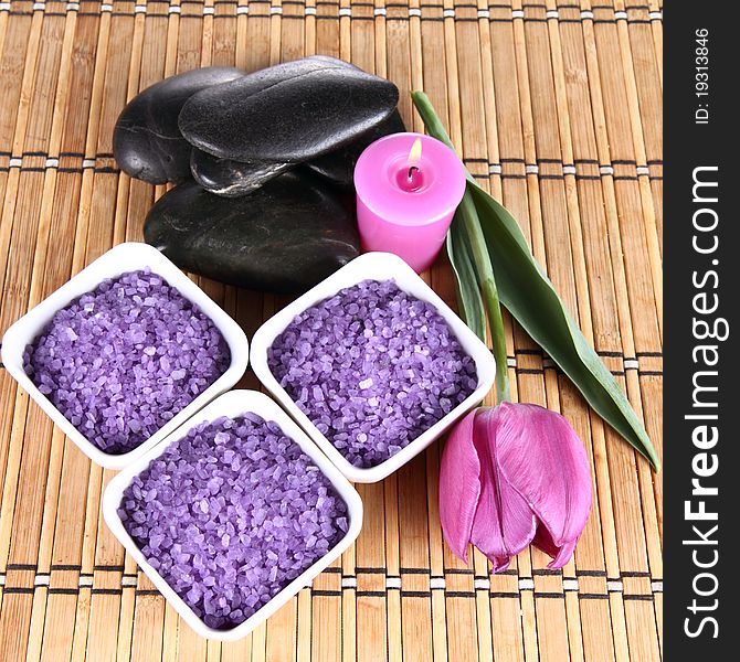 Lavender spa salt, spa stones, a candle and a tulip flower. Lavender spa salt, spa stones, a candle and a tulip flower