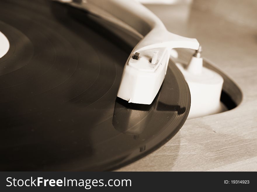 Turntable and vinyl record in close up in sepia