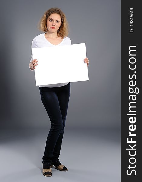 Young woman holding empty white board, on a grey background