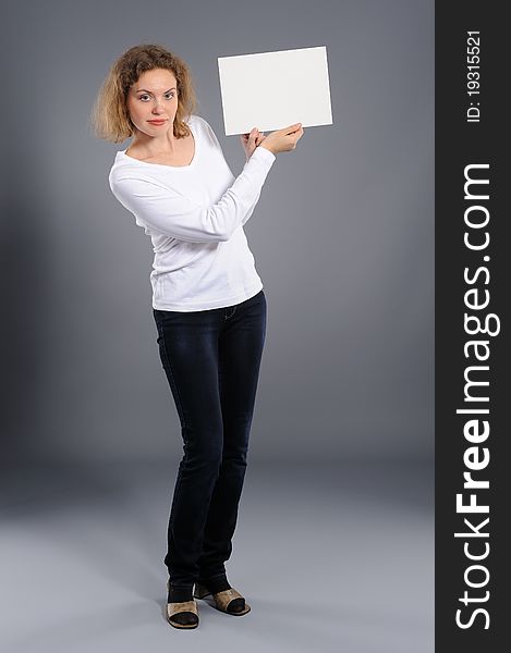 Young woman holding empty white board, on a  grey background