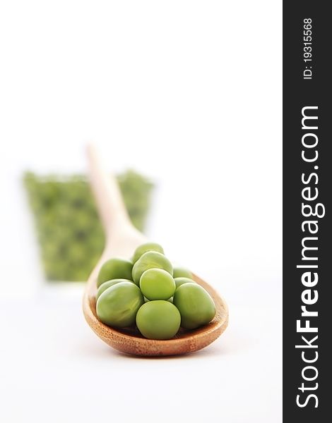 Fresh green pea on a small wooden spoon on white background with soft shadow